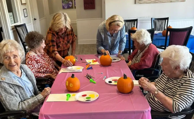 Seniors and staff enjoy pumpkin painting at a community event.