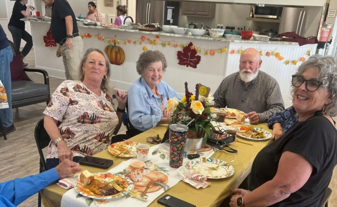 Group of smiling people dining at a fall-themed table.