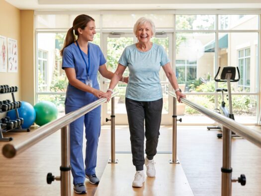 Senior resident practicing gait exercises with a physical therapist during rehabilitation after hip surgery for seniors
